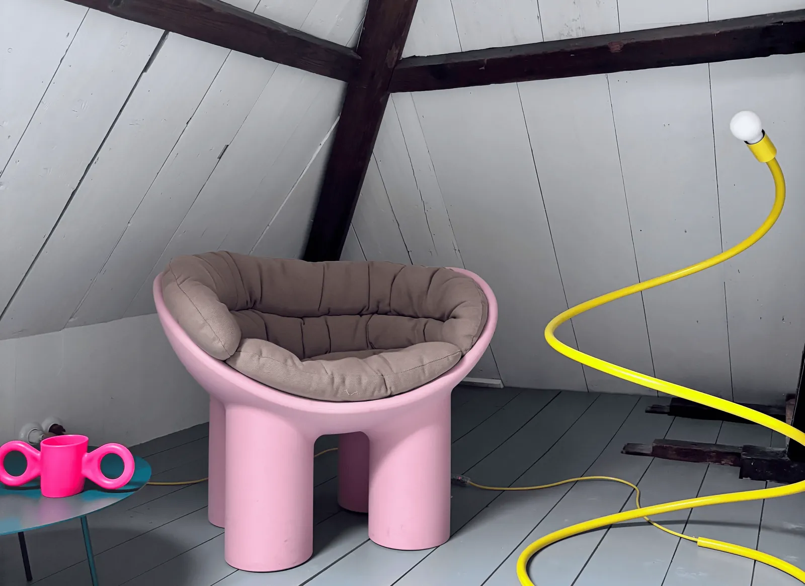 De loft met witte planken, eiken balken en een roze stoel